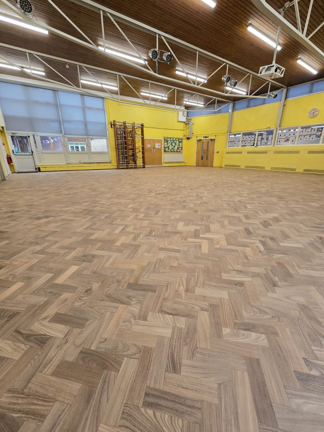 Herringbone parquet floor in a Croydon school hall after restoration