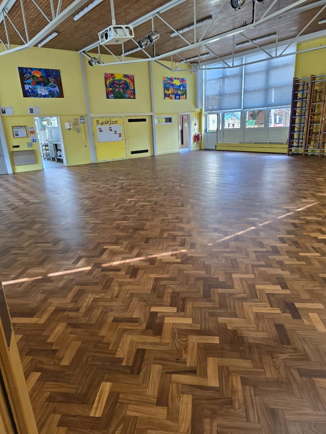 Restored darker herringbone parquet floor in a school hall in Croydon