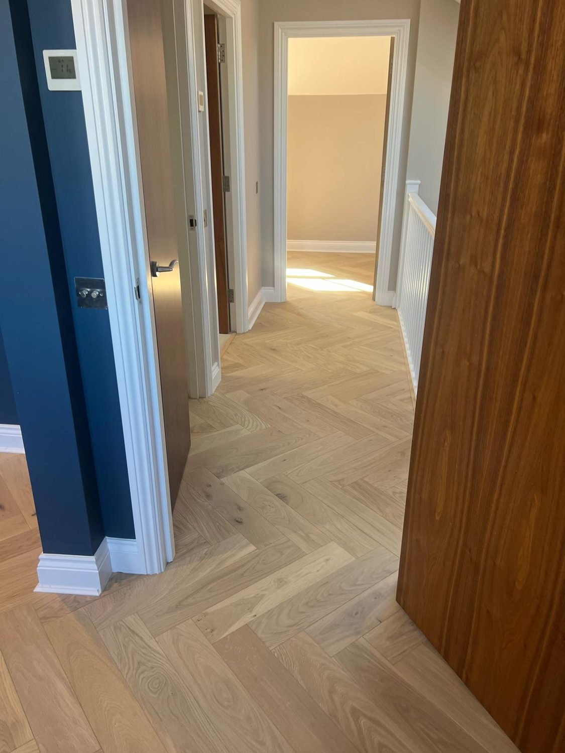 Oak herringbone flooring installed through a hallway in Hackney