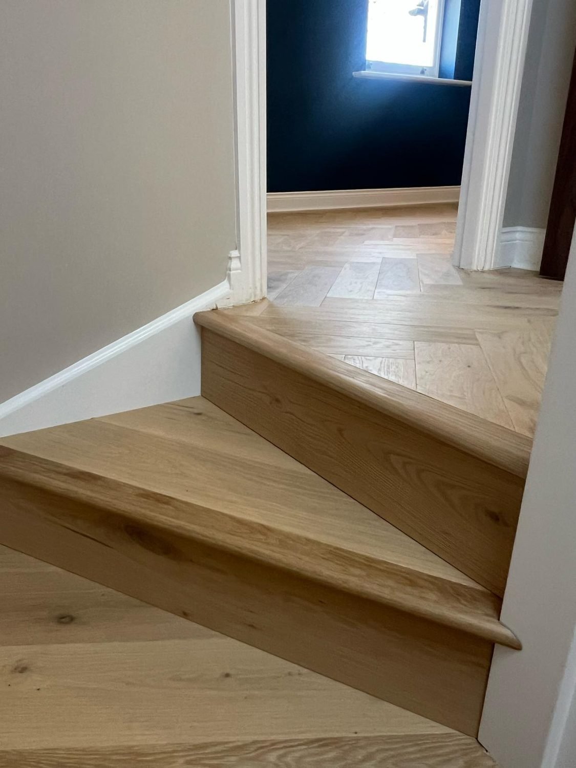 New oak herringbone floor meeting the staircase in a Hackney home